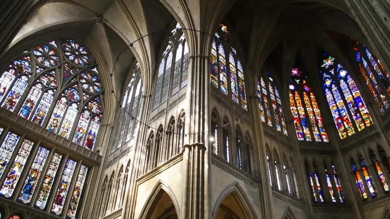 interior cathedral nave with clerestory and large stained-glass windows over arcades