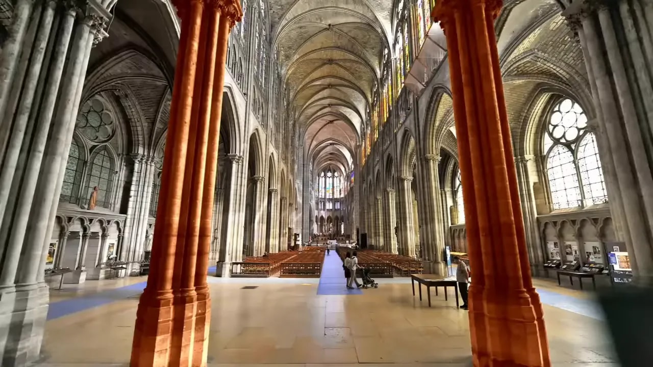 Gothic cathedral interior looking down the nave with ribbed vaults, pointed arches, clerestory stained-glass and clustered columns