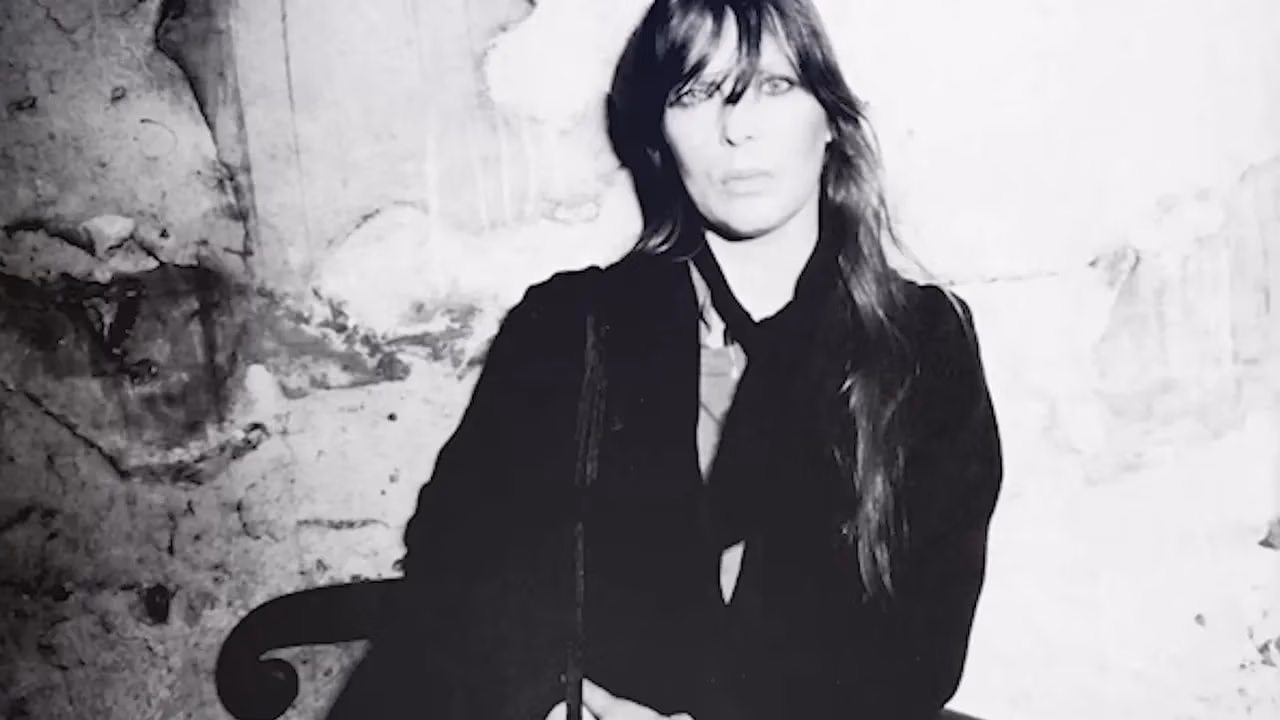 Black and white portrait of Nico standing against a textured wall